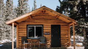 A wooden cabin with a sign reading "Aspen Suite," two chairs outside, and a door. - Aspen Cabin: Relaxing Mountain Escape | Sleeps 4 (Clearwater County)