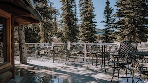 A wooden deck with outdoor seating, surrounded by tall trees and a clear view of the mountains. - Aspen Cabin: Relaxing Mountain Escape | Sleeps 4 (Clearwater County)