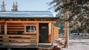 Ein rustikales Blockhaus mit Metall-Dach und einer Holzterrasse, mit einem Schild, auf dem "SPRUCE" steht.