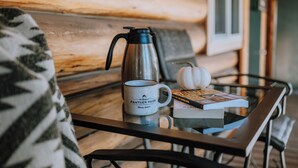 Ein Glastisch mit Kaffeekanne, Tasse und Buch in einer Holzhütte.