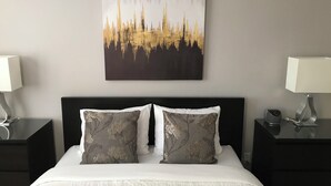 Ein Hotelzimmer mit Bett, zwei Nachttischen, einem Wandbild und zwei Lampen.