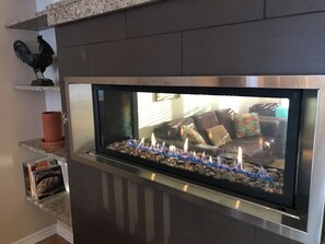 A modern fireplace with a glass front, surrounded by a stone base and a metal frame. - 3-bedroom apartment, a 5-minute walk from the Saint-Michel metro station (Montréal)