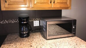 Eine Küche mit Holzausstattung, einer Kaffeemaschine und einer Mikrowelle auf einer Granitarbeitsplatte.