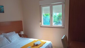A hotel room with a bed, a desk, and a window with blinds. - Apartments Lux Lukić Utjeha - One bedroom apartment (Utjeha)