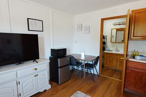 A compact kitchen with a microwave, refrigerator, and a dining table with chairs. - Homestead Motel & RV (Sloan)