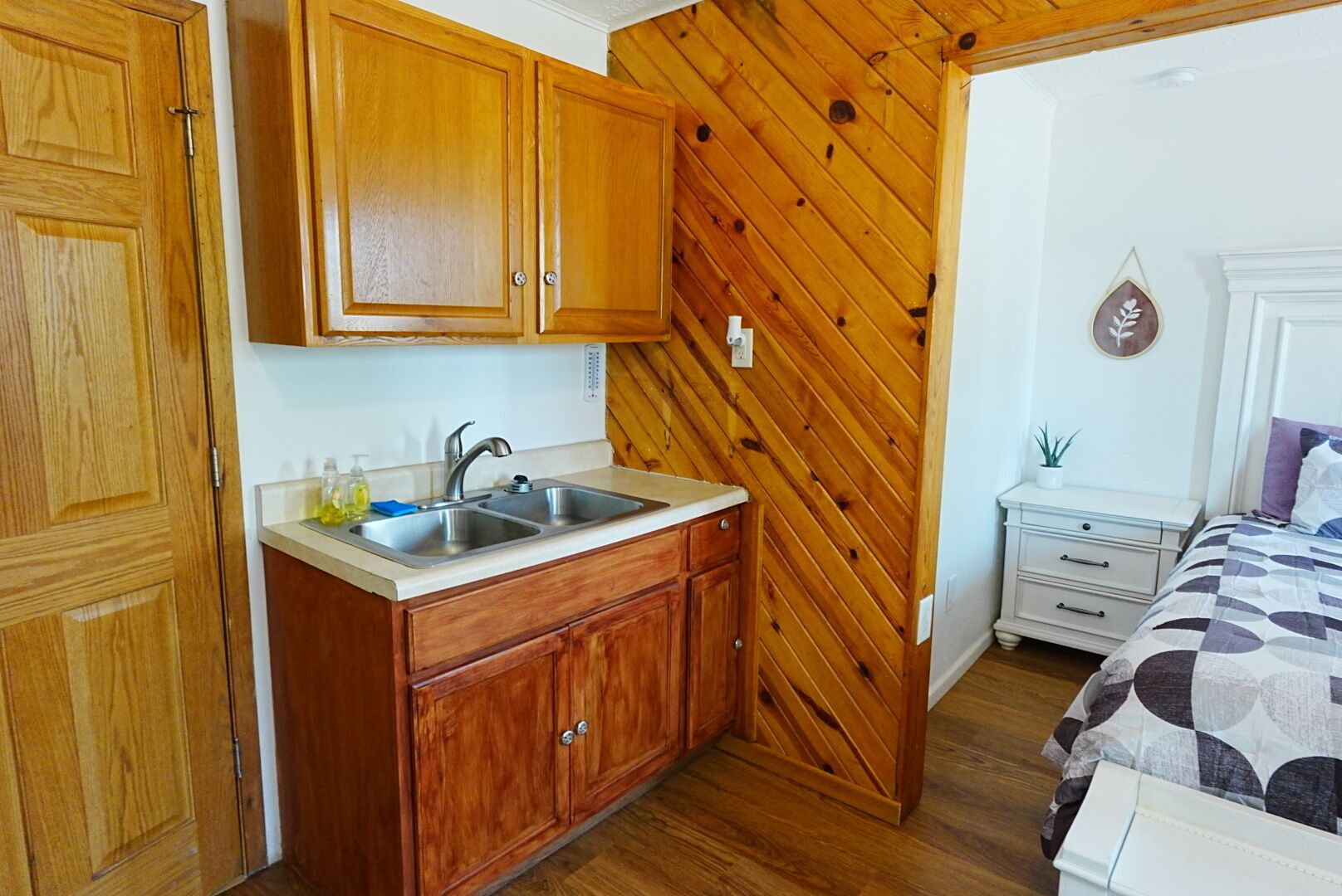 Una cucina compatta con mobili in legno, un lavello a due scomparti e un piano di lavoro.
