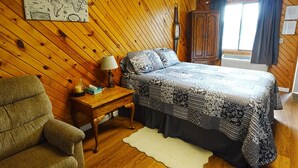 A room with a bed, a desk, a chair, a map on the wall, and a window with curtains. - Homestead Motel & RV (Sloan)
