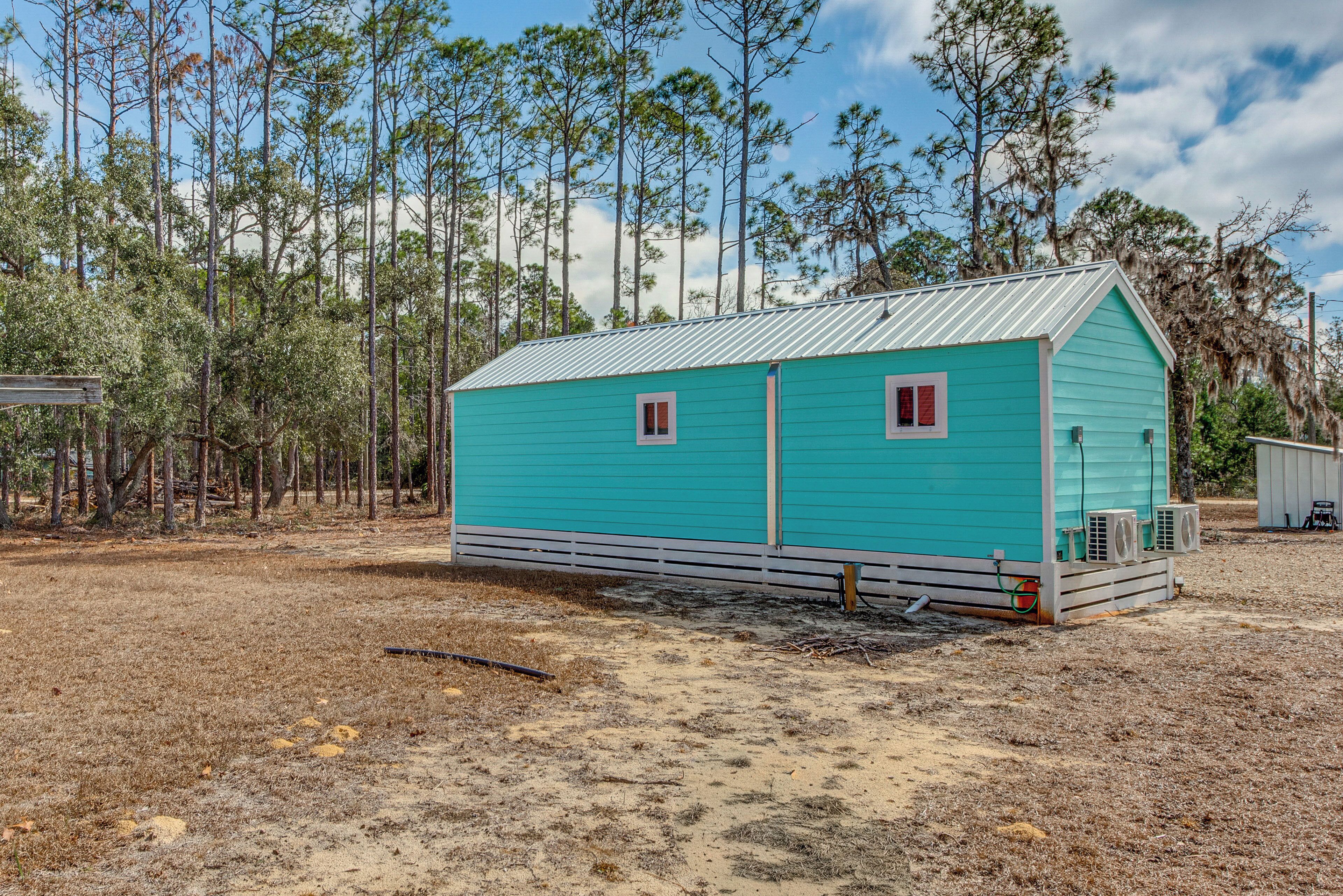 A small, single-story building with a metal roof, surrounded by a forested area.