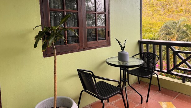 A balcony with a potted plant, two chairs, and a table. - Near Rodney Bay! Breezy, Beachy and Spacious 1-Bedroom Unit. (Castries)