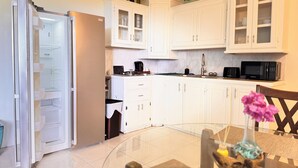 A modern kitchen with white cabinets, a built-in microwave, and a refrigerator. - Near Rodney Bay! Breezy, Beachy and Spacious 1-Bedroom Unit. (Castries)