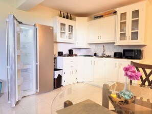 A modern kitchen with white cabinets, a built-in microwave, and a refrigerator. - Near Rodney Bay! Breezy, Beachy and Spacious 1-Bedroom Unit. (Castries)