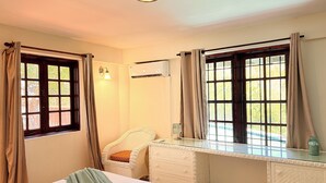 A bedroom with a bed, a desk, a chair, and two windows with curtains. - Near Rodney Bay! Breezy, Beachy and Spacious 1-Bedroom Unit. (Castries)