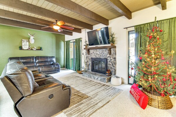 A living room with a leather sofa, a fireplace, a Christmas tree, and a television. - Nat'l Forest Retreat at 'The Nest at Pinetop' (Pinetop)