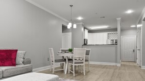 A modern kitchen with white cabinets, a dining table, and chairs.