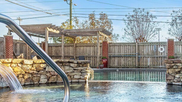 A swimming pool with a stone wall and a wooden deck.