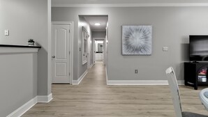 A hallway with a wooden floor, white walls, and a ceiling light.