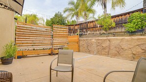 A patio area with a wooden fence, a stone wall, and a chair. - Sip, Hike & Explore: Quiet SoCal Studio w/ Patio! (Winchester)