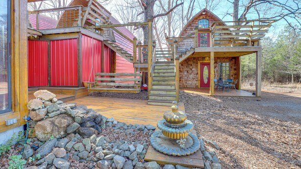 A rustic cabin with a wooden deck, a red door, and a stone fountain. - 1 Mi to TIEC: Peaceful Mountain Cabin (Mill Spring)