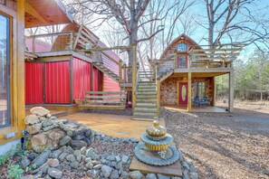 A rustic cabin with a wooden deck, a red door, and a stone fountain. - 1 Mi to TIEC: Peaceful Mountain Cabin (Mill Spring)