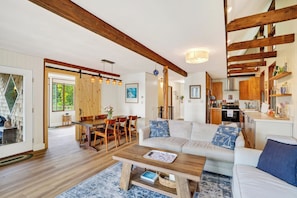 Ein gemütliches Wohnzimmer mit Sofa, Couchtisch und Essbereich mit Stühlen.