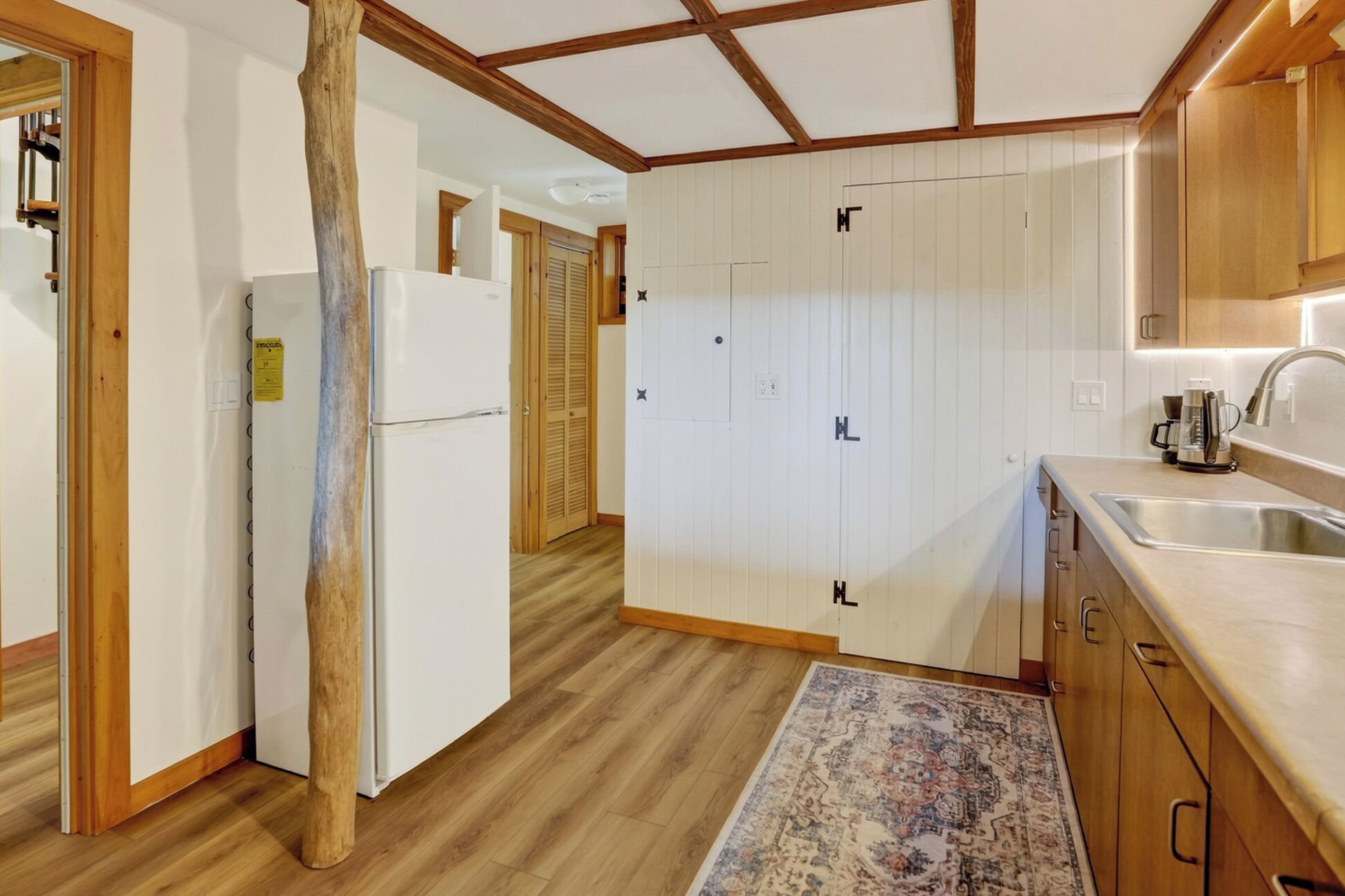 Une cuisine avec des meubles de rangement en bois, un réfrigérateur et un évier.