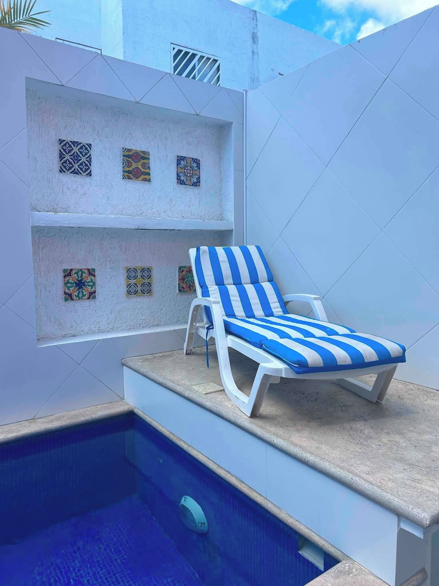 Un espace aménagé au bord de la piscine, avec un fauteuil de relaxation et des carreaux décoratifs sur le mur.