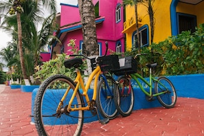 Ein Fahrrad neben einem farbenfrohen Gebäude mit blauem Sockel und einem roten Ziegelweg.