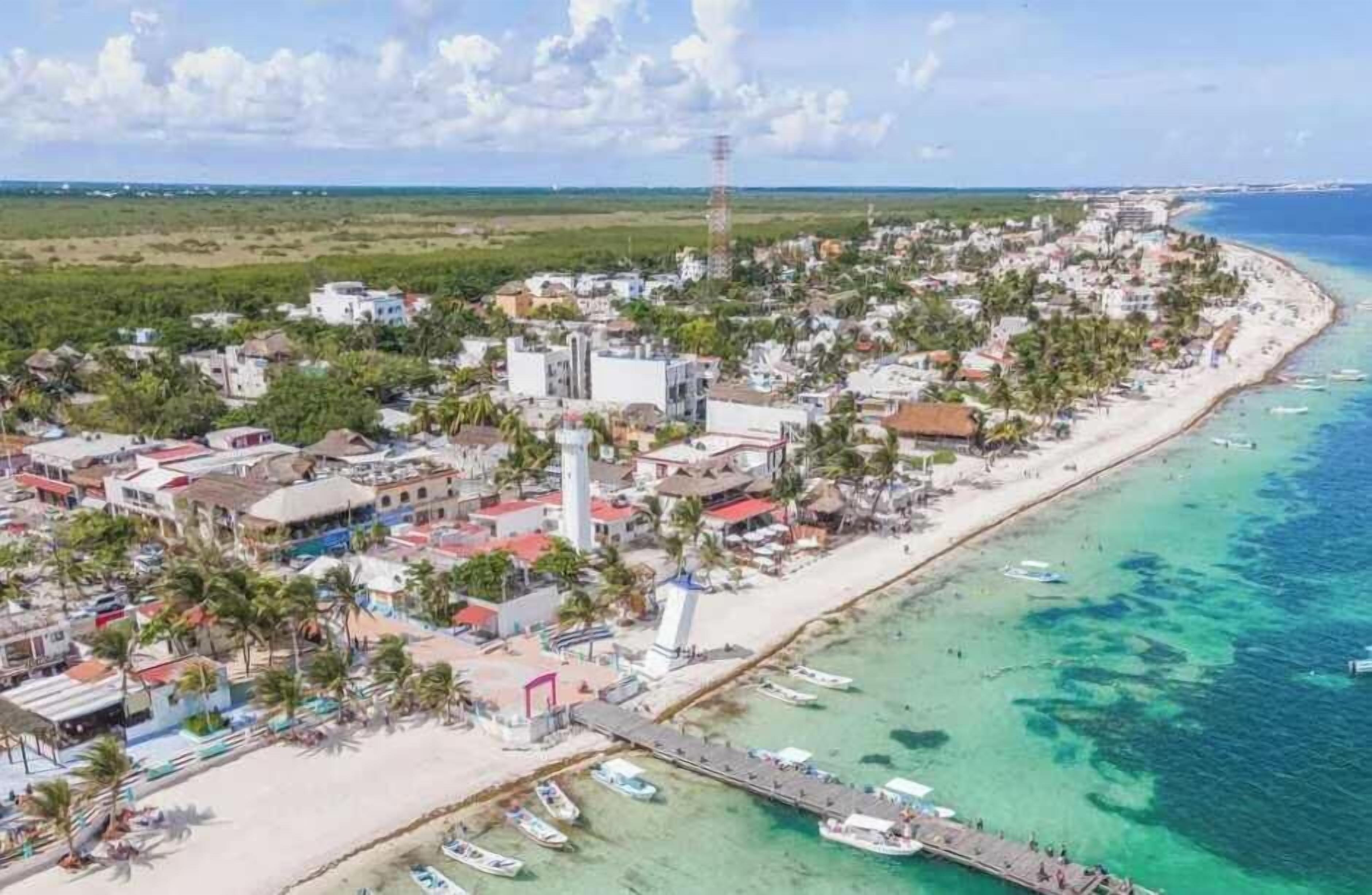 A coastal town with a beach, boats, and a lighthouse.