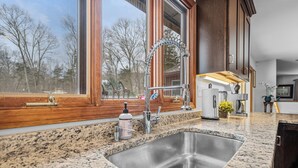 Una cocina con encimera de granito, pileta de acero inoxidable y muebles de madera.
