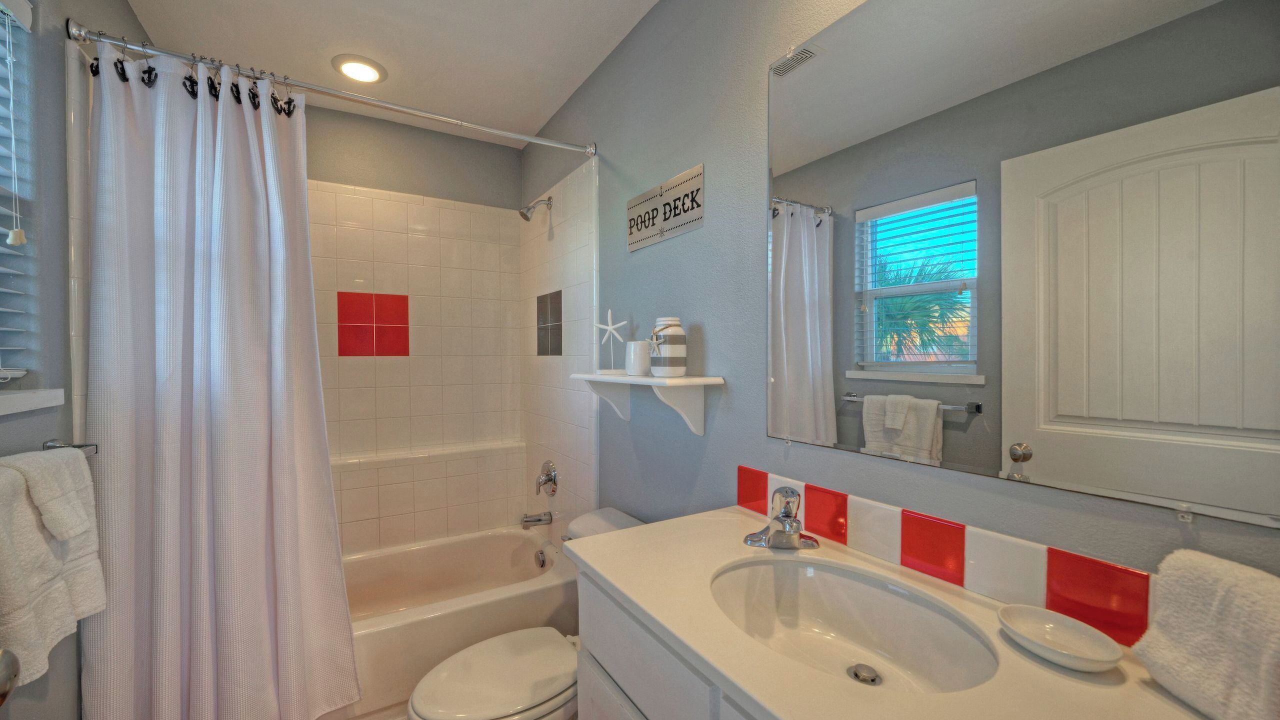 Un baño con ducha, inodoro, lavabo y un letrero que dice 'POOP DECK'.