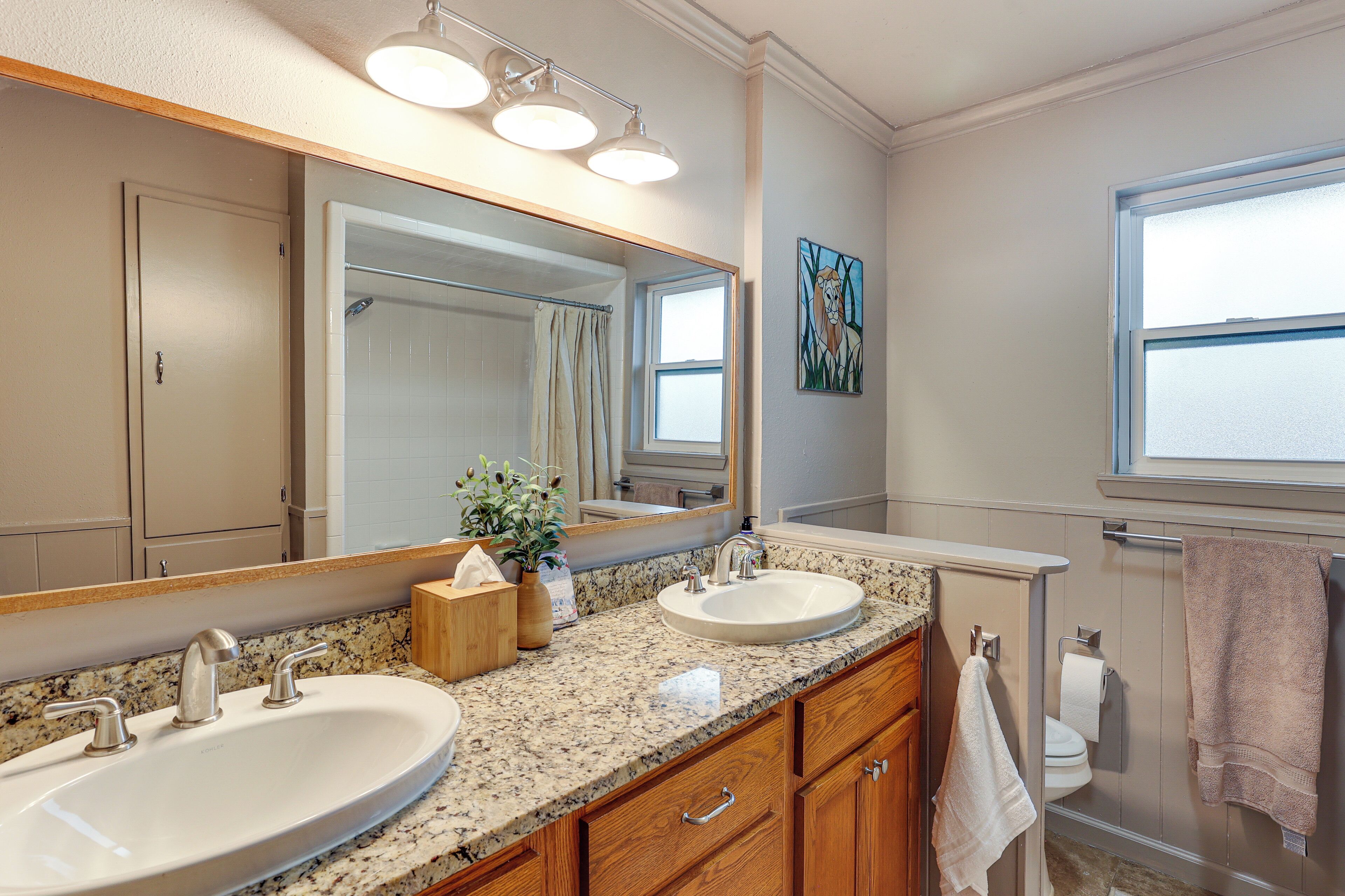 A bathroom with two sinks, a large mirror, and a window.
