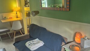 A room with a sofa, a desk, a chair, a table with a lamp, and a mirror. - Treelined street, hidden gem in a bamboo forest.  Walk to coffee shops/eateries! (San Marcos)