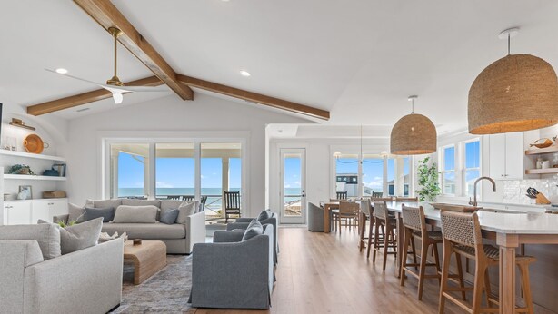 A spacious living area with a large sofa, a coffee table, and a dining area with bar stools. - Paradise at the Pointe (Ocean Isle Beach)