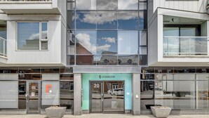A modern building with large glass windows reflecting the sky and nearby structures. - Magnificent downtown Penthouse with free underground parking (Québec)