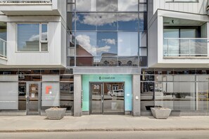 A modern building with large glass windows reflecting the sky and nearby structures. - Magnificent downtown Penthouse with free underground parking (Québec)
