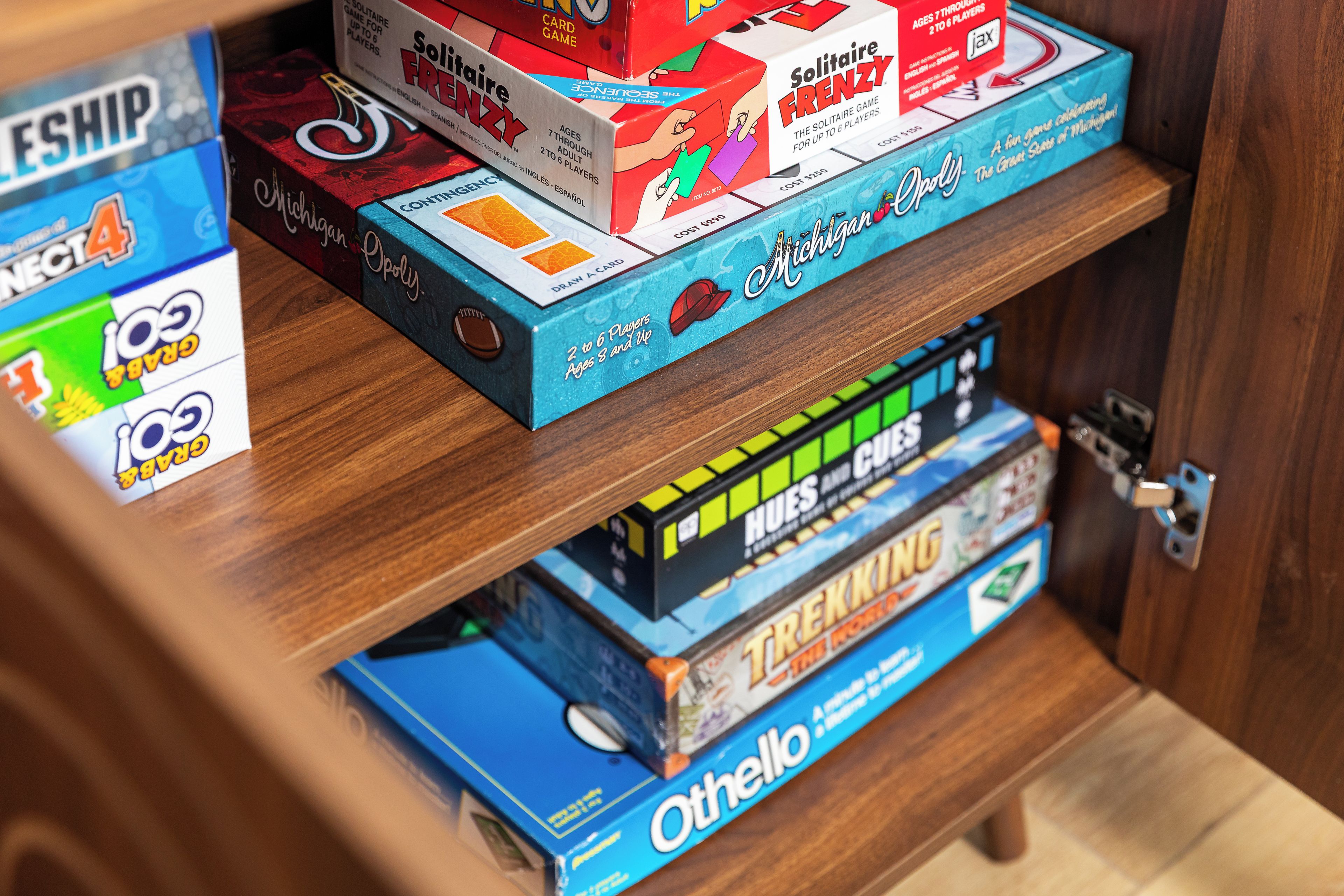 A shelf with various board games including Monopoly, Catan, and Ticket to Ride.