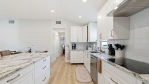 Una cocina moderna con armarios blancos, encimera de granito y una isla central.