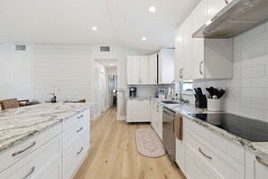 A modern kitchen with white cabinetry, a granite countertop, and a central island. - Poolside Paradise with Brand New Spa & Saltwater Pool – Minutes to Siesta Key (Sarasota)