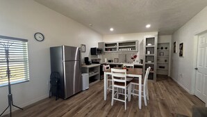 Eine kleine Küche mit Kühlschrank, Mikrowelle und einem Holzespeisebereich mit Stühlen.