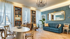 Ein Wohnzimmer mit rundem Tisch, Stühlen, einer Couch und einem Bücherregal.
