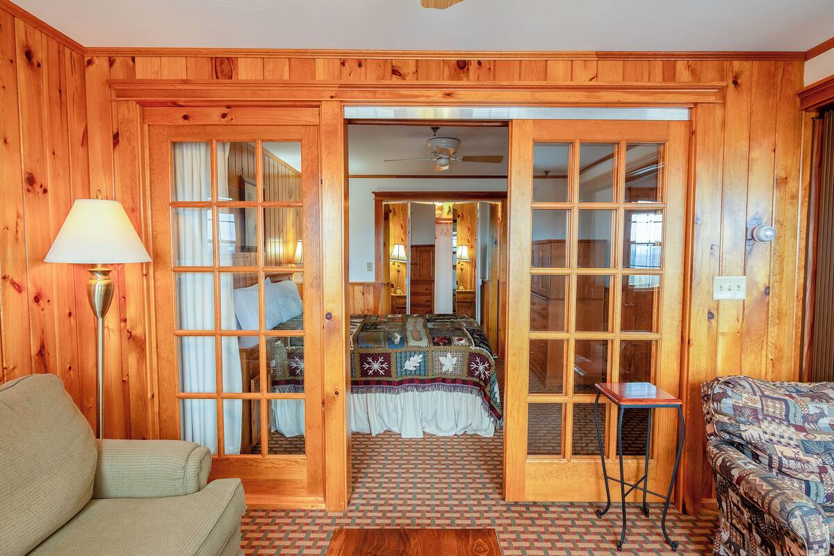 A wooden-paneled room with a bed, a sofa, and a small table.