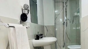 Ein Badezimmer mit einem weißen Waschbecken, einer Duschkabine aus Glas und einer weißen Toilette.