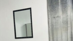Ein Zimmer mit einem Sessel, einem Spiegel und einem Vorhang.