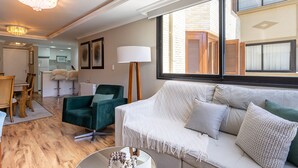 Un salon moderne avec un canapé blanc, un fauteuil vert et un coin repas doté de meubles en bois.
