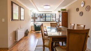 A dining area with a wooden table and chairs, a radiator, and a view of the outside. - Apto com Vaga Aquecimento e Piscina na Vila Su a (Gramado)