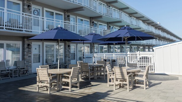 A patio area with outdoor seating and umbrellas, overlooking a building with multiple balconies.