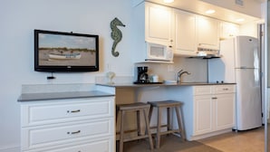 A modern kitchen with white cabinetry, a microwave, a refrigerator, and a coffee maker.