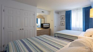 A hotel room with two beds, a dresser, a television, and a window with curtains.