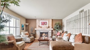 A spacious living room with a fireplace, comfortable seating, and a large window providing natural light.