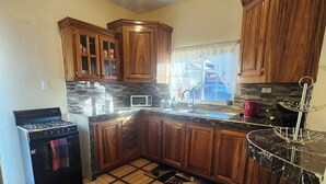 A kitchen with wooden cabinets, a microwave, a gas stove, and a tiled floor.